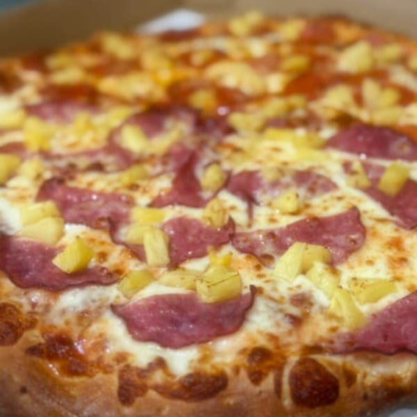 Close-up of a Fiesta Pizza with pepperoni, pineapple, and melted cheese.