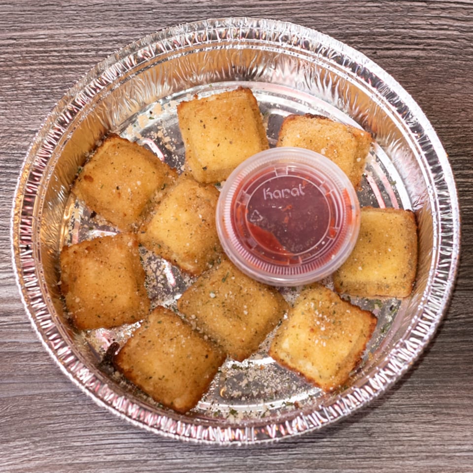 Golden brown toasted ravioli with seasoning and a side of red sauce in a foil container.